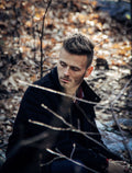 Close-up editorial portrait of a man wearing a dark wool overcoat outdoors