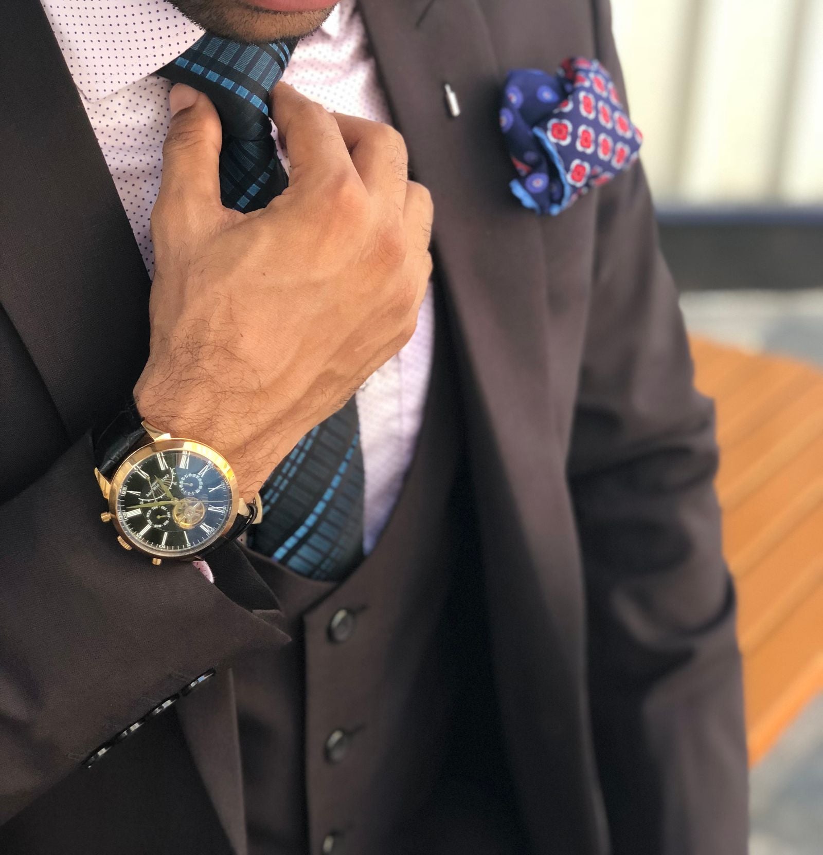 Elegant close-up of a man in a designer suit adjusting his silk necktie