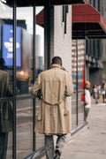 Stylish man in a trench coat walking past a storefront