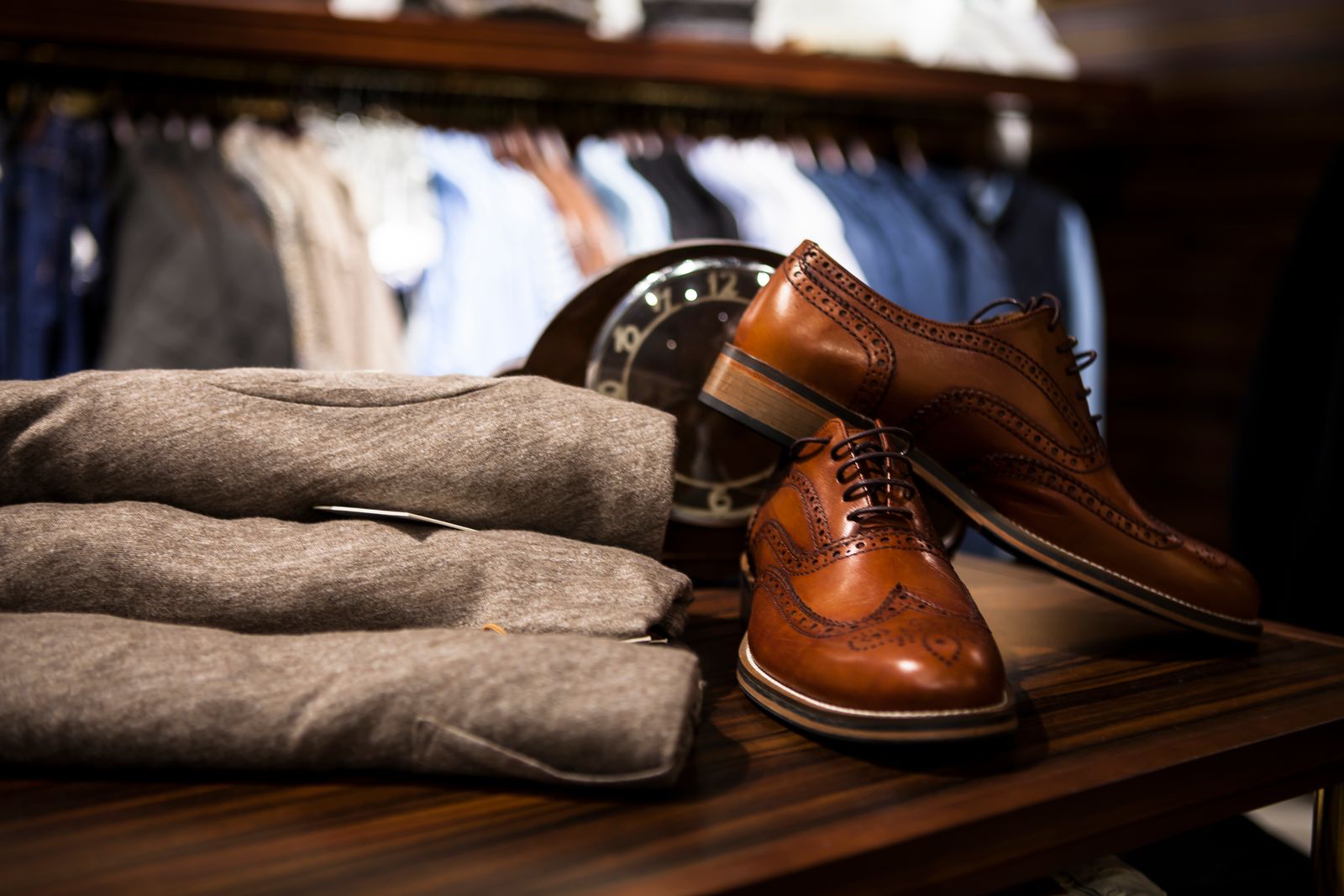 Pair of brown leather wingtip shoes styled beside grey apparel
