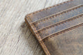 Detailed close-up of a brown leather bifold wallet showing fine stitching