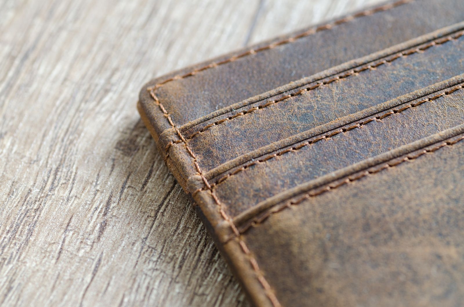 Detailed close-up of a brown leather bifold wallet showing fine stitching