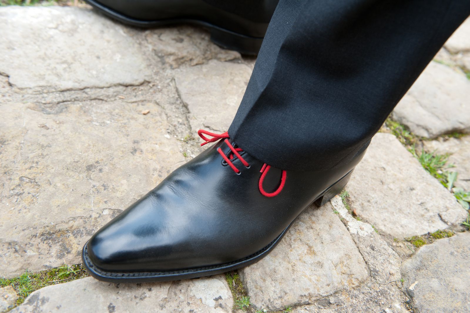 Close-up of polished black leather oxford dress shoes on cobblestone pavement